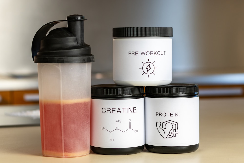 How to Choose the Right Gym Water Bottle or Shaker for Your Workouts 1 three containers of protein powder next to a blender