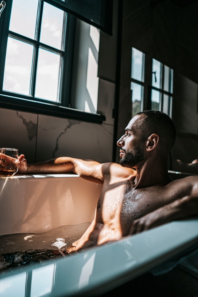 Home 4 a man sitting in a bathtub holding a glass of wine