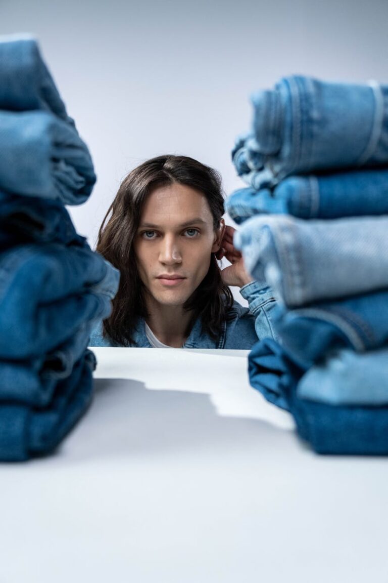 man posing beside denim clothes