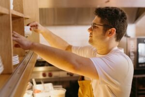 A man in a white shirt is putting something on a shelf