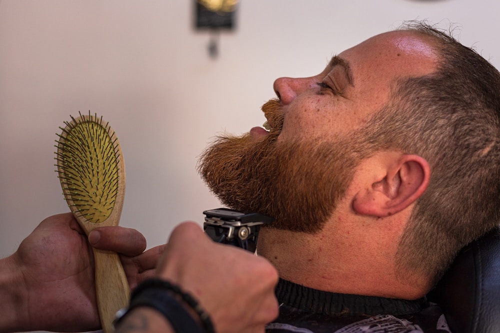 Home 6 a bearded man getting his hair cut with a brush