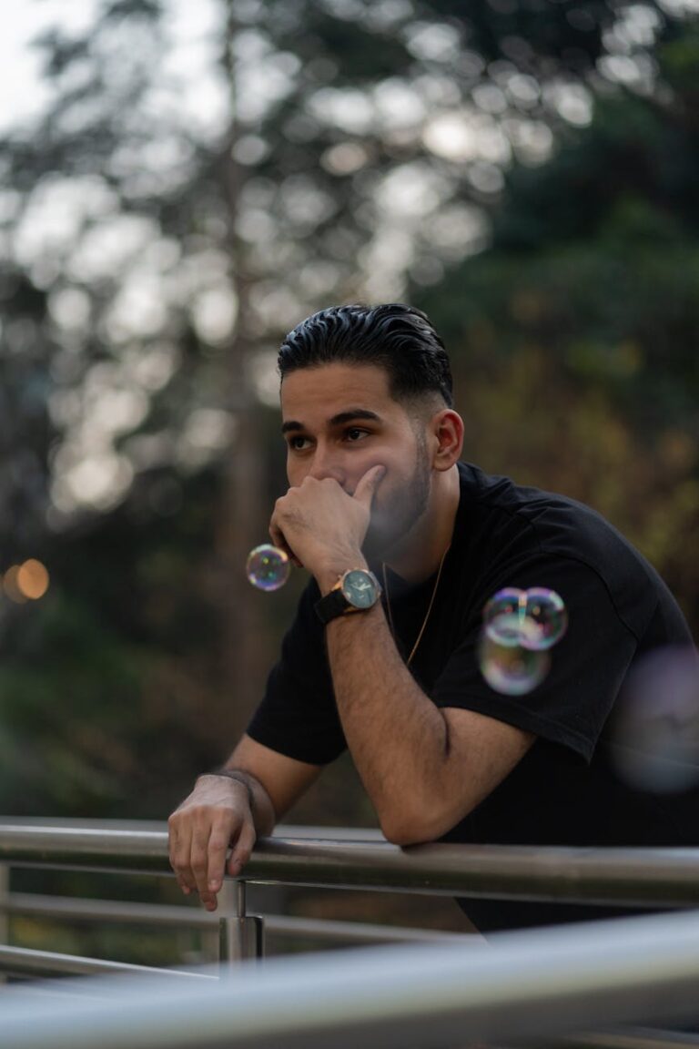 a man is leaning against a railing and blowing bubbles